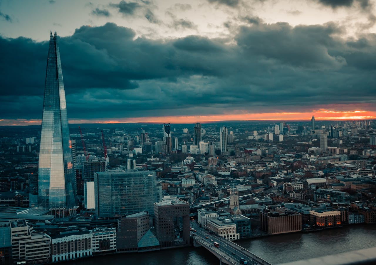 A breathtaking dusk view of London's skyline with The Shard and River Thames under a dramatic sky.